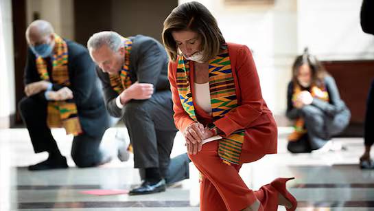 Nancy Pelosi kneeling in West African print in 2020