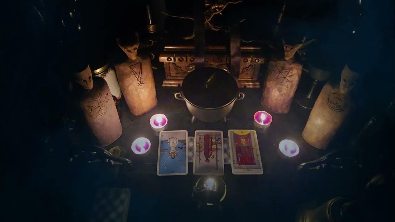 A ceremonial altar with four horned figurines marked with a sigil on their chest, four lit tea candles, three Tarot cards, and a small cooking pot