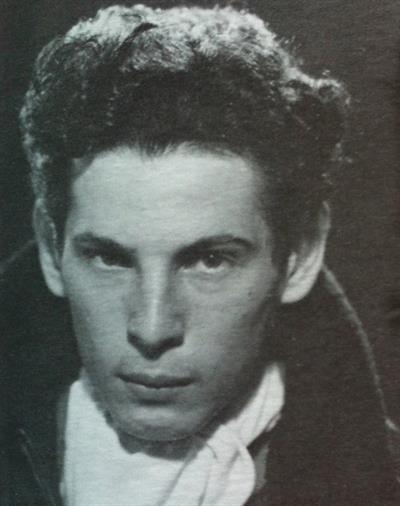 black and white photo Anton LaVey as a young man with a full head of hair, no facial hair but it looks like he's wearing a cape?