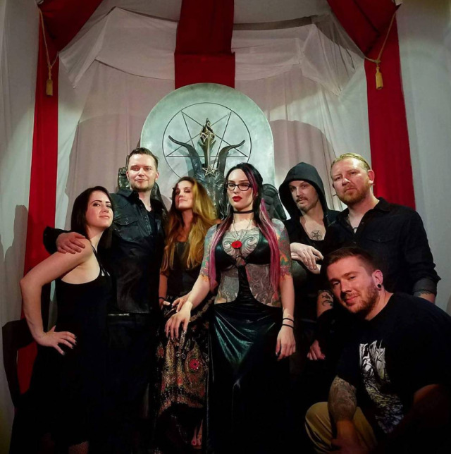 Photo of The Satanic Temple members gathered around the statue of Baphomet with children. Included is Lucien Greaves and Ash Astaroth, but also Stu De Haan and MIchelle Shortt